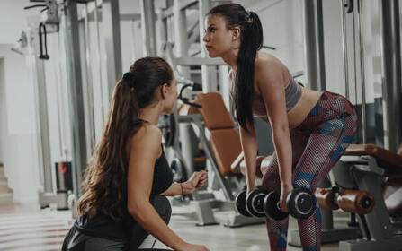 Personal trainer guiding a client through a fitness workout at a gym