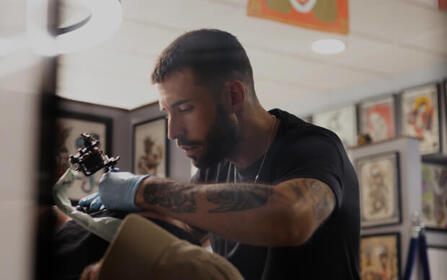 Tattoo artist inking a client’s arm inside a modern studio